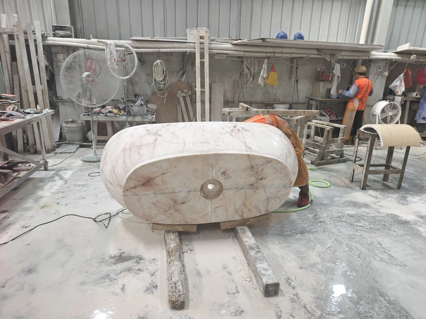 Stone craftsperson refining the machined Calacatta Rosa marble bathtub in the finishing workshop. Stone craftsperson refining the machined Calacatta Rosa marble bathtub in the finishing workshop.